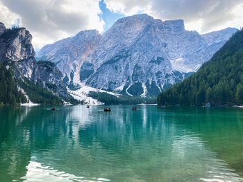 Scenic view of lake by snowcapped mountains against sky