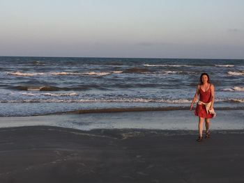 Woman standing on beach against sky