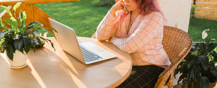 Midsection of woman using laptop while sitting on table