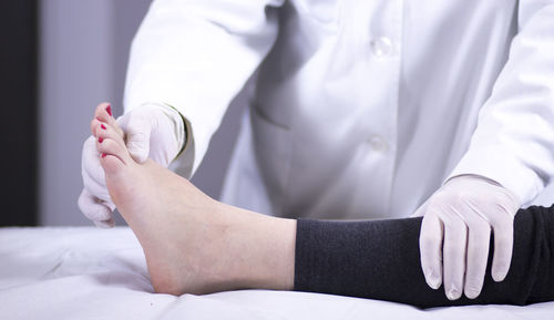 Midsection of doctor examining patient barefoot in hospital