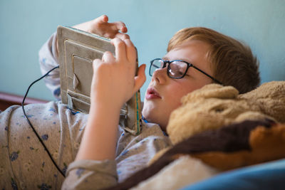 Close-up of boy using digital tablet while lying on bed