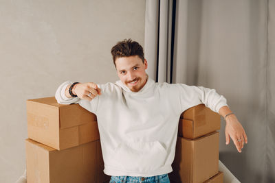 Portrait of smiling young woman standing against wall