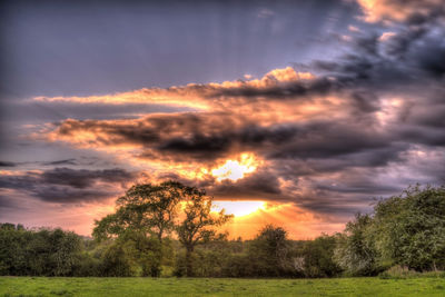 Scenic view of dramatic sky over land during sunset