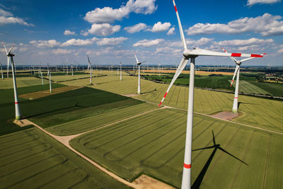 Wind turbines on field against sky