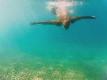 Shirtless man swimming in turquoise sea