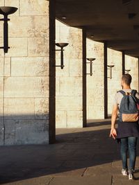 Rear view of young man with backpack walking on footpath