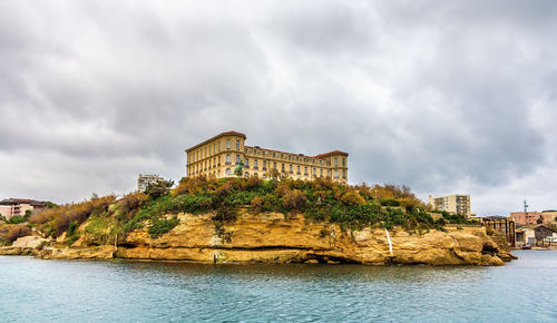 Building by river against cloudy sky