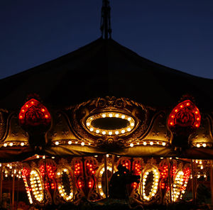 Low angle view of illuminated carousel against sky at night