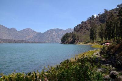 Scenic view of sea and mountains against clear blue sky