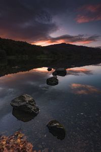 Scenic view of rocks in lake against sky during sunset