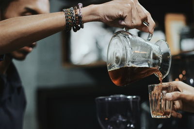 Midsection of man pouring wine in glass