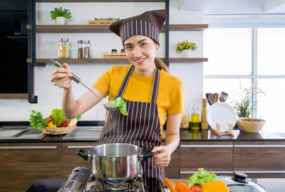 Woman holding food while standing at kitchen