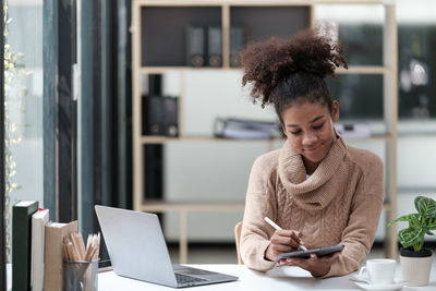 Portrait of young woman using laptop at home