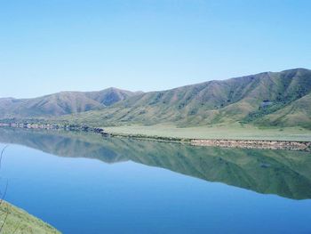 Scenic view of lake and mountains against clear blue sky