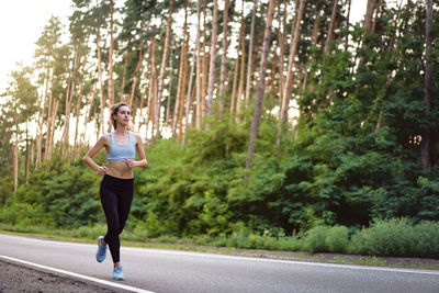 Woman running on road in forest