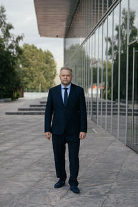 Full length portrait of businessman standing on footpath