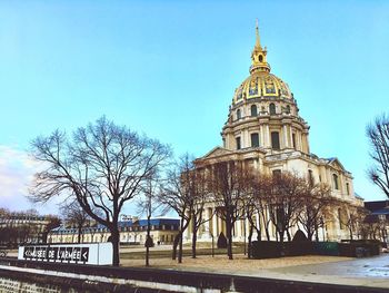 Bare trees and buildings against sky