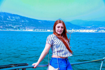 Portrait of smiling young woman standing against sea