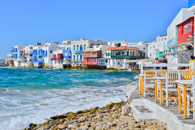 Rolling and breaking waves, chairs and tables at little venice quarter, mykonos island, greece