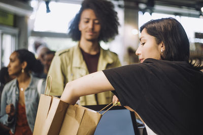 Saleswoman packing bag while customer standing at grocery store checkout