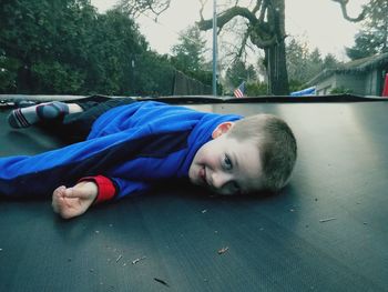 Portrait of boy lying on trampoline in park