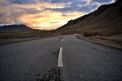 Road amidst mountains against sky during sunset