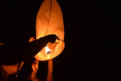 Close-up of hand holding illuminated lantern at night