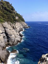 Rock formation on sea against blue sky