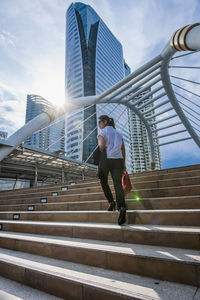 Low angle view of person on staircase in city against sky