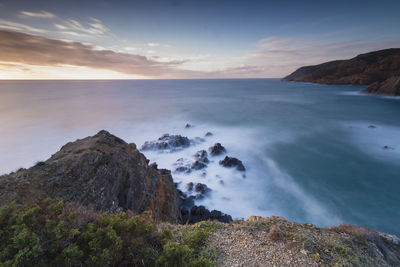 Scenic view of sea and mountains against sky during sunset