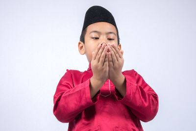 Cute boy wearing maroon traditional clothing standing against white background