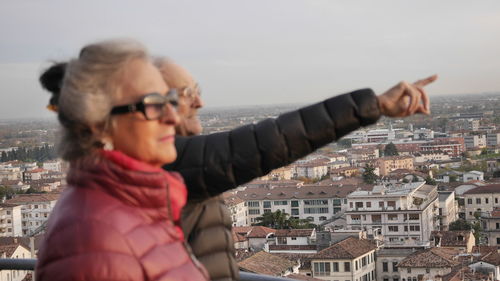 Senior man with woman pointing while standing against cityscape