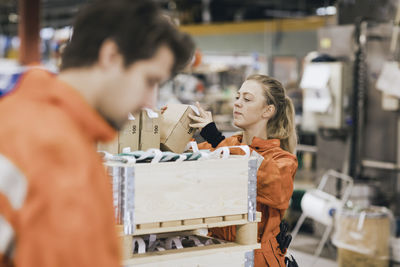 Female blue-collar worker arranging boxes in factory warehouse