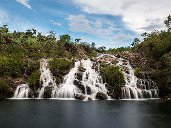 Scenic view of waterfall in forest against sky