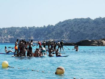 People by swimming pool against sea and mountains