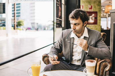 Businessman using smart phone while sitting at cafe