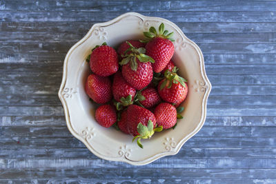 High angle view of strawberries in bowl on blue table