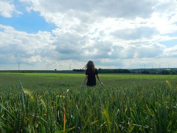 Rear view of woman standing on wheat field