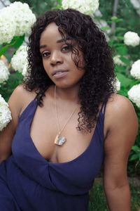 Portrait of beautiful young woman standing against plants in park