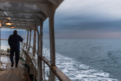 Man standing on pier at sea