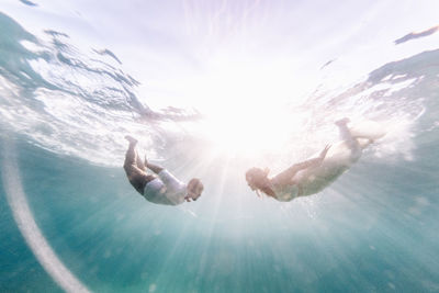 People swimming in sea against sky