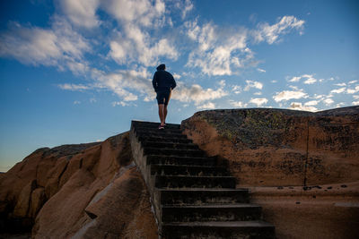 Rear view of man walking on mountain against sky