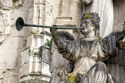 Statue of angel with trumplet on the facade of the ancient church of the holy cross in coimbra