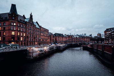 Canal amidst buildings in city against sky