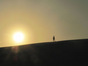Silhouette person standing on field against sky during sunset