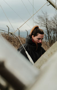 Portrait of young woman standing by railing