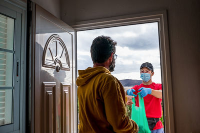 Rear view of men standing against window