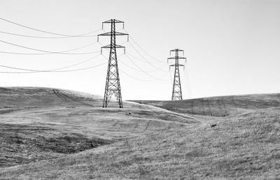 Electricity pylon on field against clear sky