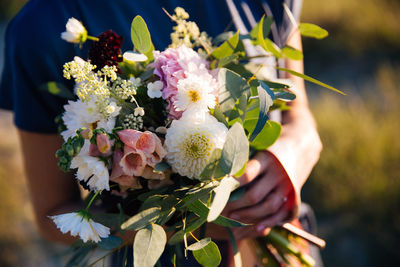 Close-up of hand holding bouquet of flowering plant