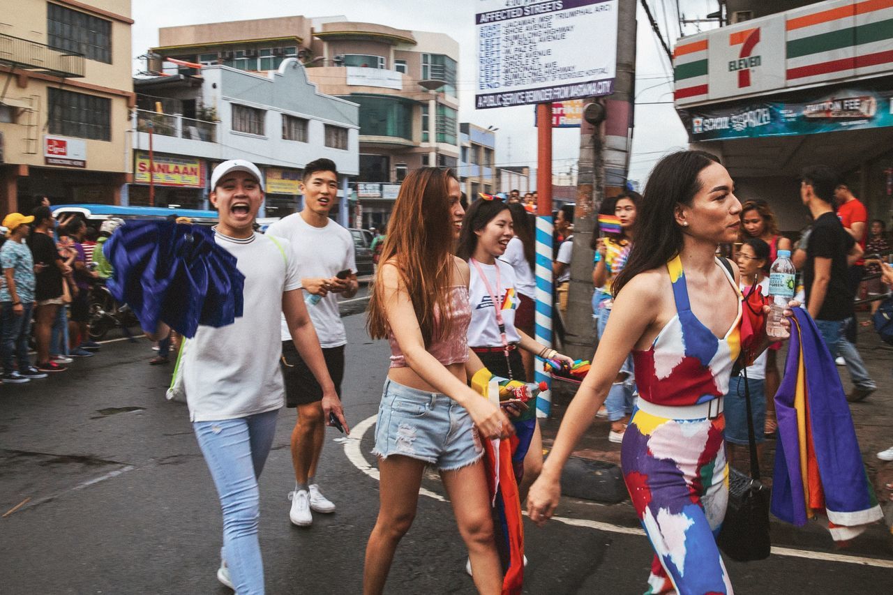 group of people, city, architecture, building exterior, adult, women, city life, men, day, three quarter length, young adult, crowd, street, smiling, people, built structure, casual clothing, group, enjoyment, teenager